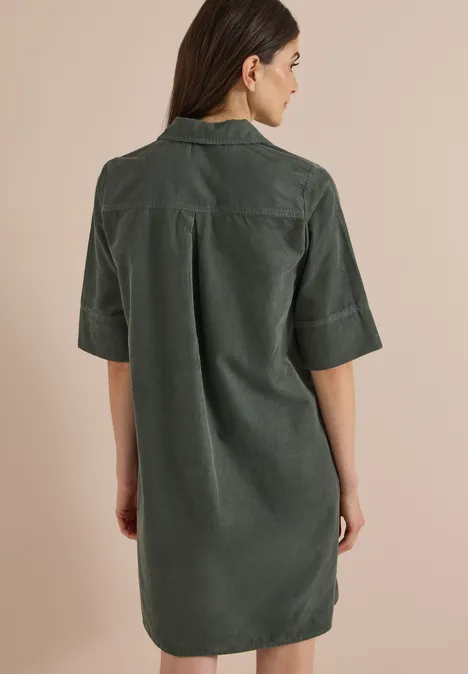Rückansicht einer Frau in einem dunkelgrünen, kurzärmligen Hemdkleid aus Cord.
