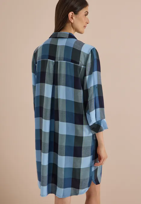 Frau von hinten/seitenansicht in lockerem blau-weiß-schwarz kariertem Hemdkleid mit langen Ärmeln.