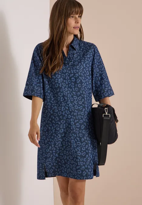 Kniehoge jurk met luipaardprint Dark blue wash Vrouw in losvallende donkerblauwe midi-hemdjurk met subtiel dessin en korte mouwen, met zwarte schoudertas.