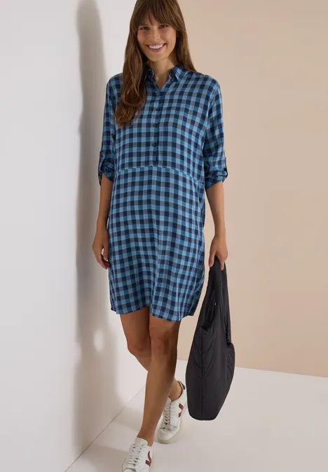 Knie-lange jurk met een fijn ruitjespatroon easy blue Lächelnde Frau in blau-kariertem Hemdkleid, Sneakers und Tasche.