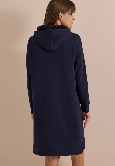Rückenansicht einer Frau in einem dunkelblauen Kapuzenkleid.