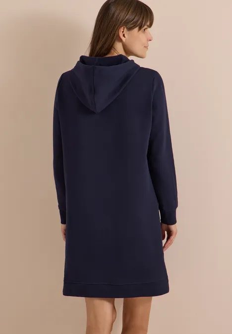 Frau von hinten in schlichtem dunkelblauem Kapuzenkleid.