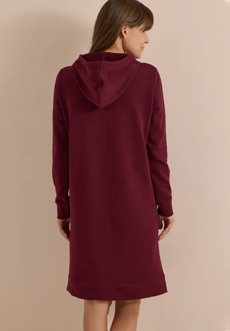 Rückenansicht einer Frau in weinrotem Kapuzenkleid mit langen Ärmeln.