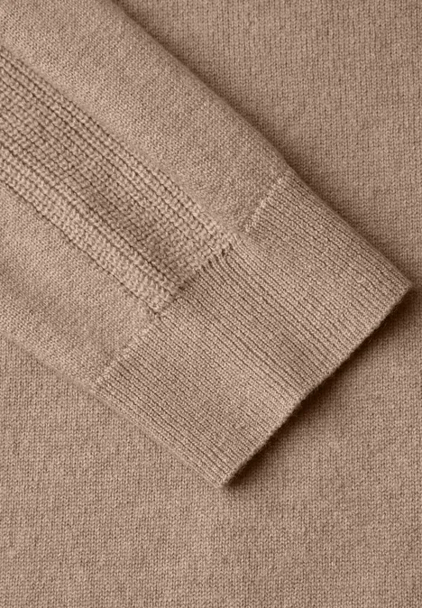 Nahaufnahme eines beigen Strickpullovers mit Rippenbündchen am Ärmel