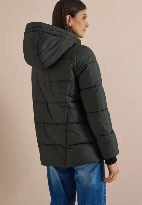 Frau trägt schwarze gesteppte Daunenjacke mit Kapuze, von hinten gesehen.