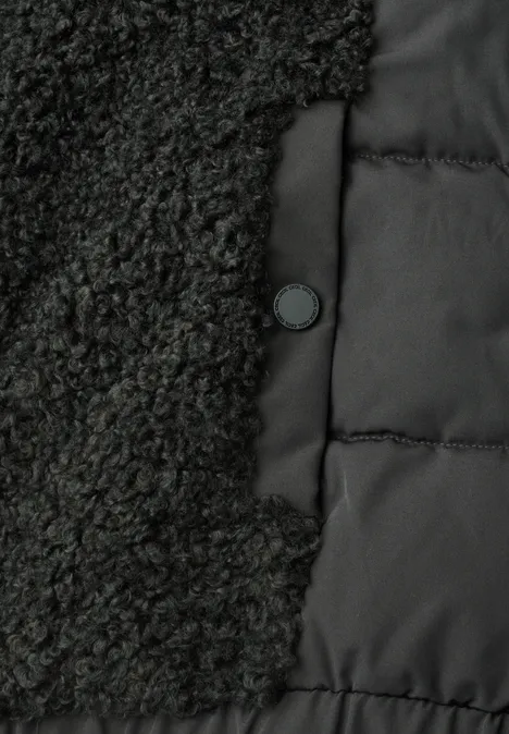 Nahaufnahme einer schwarzen Jacke mit Fleece- und Steppstoff-Einsätzen und einem Druckknopf.