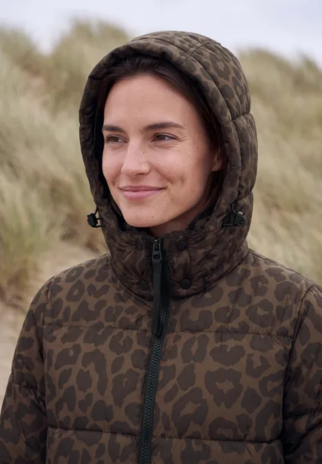 Steppjacke mit Kapuze und Reißverschluss dark toffee brown Eine lächelnde Frau in camouflage Steppjacke mit Kapuze vor Dünen