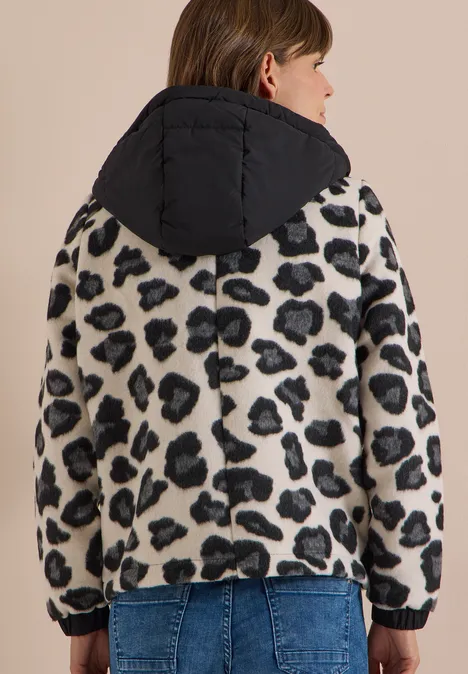 Frau von hinten in Leoprint-Fleecejacke mit schwarzer Kapuze und Jeans.