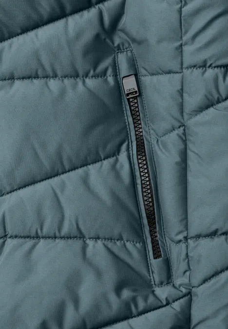 Grüne gesteppte Jacke mit Reißverschluss-Tasche in Nahaufnahme.