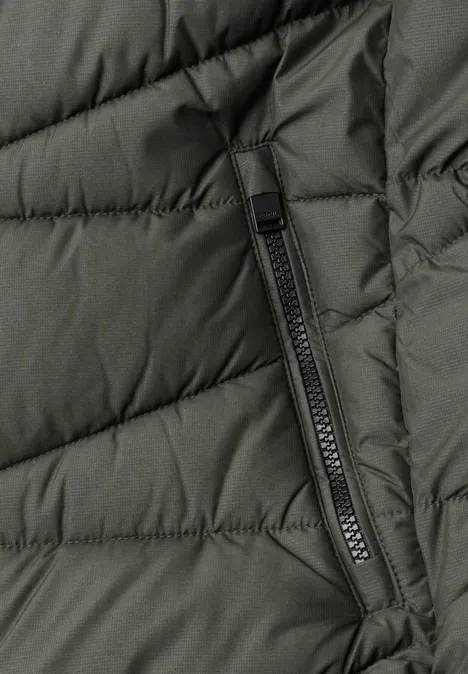 Nahaufnahme einer olivgrünen, gesteppten Jacke mit senkrechter Reißverschlusstasche.