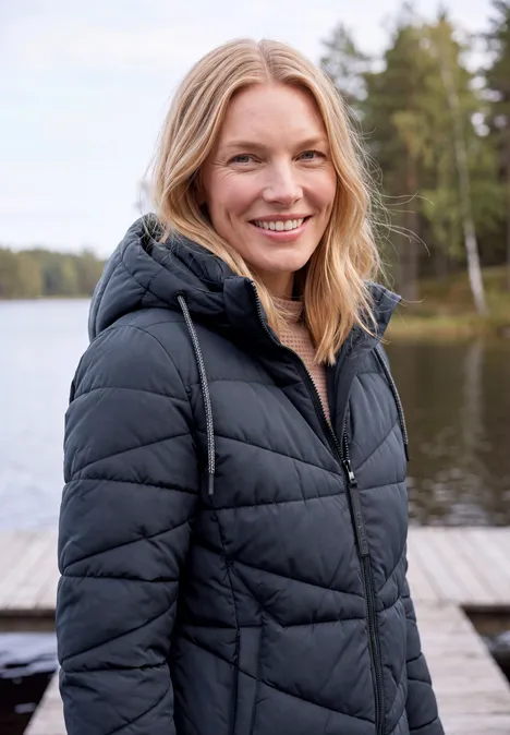 Steppjacke mit Kapuze und Zipper dark navy blue Eine lächelnde Frau in schwarzer Steppjacke steht auf einem Steg an einem ruhigen Waldsee.