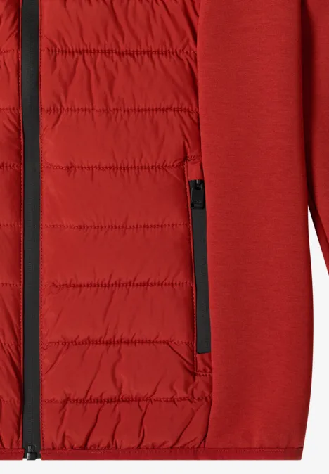 Gros plan d’une veste rouge avec doublure matelassée, isolante et poche zippée.