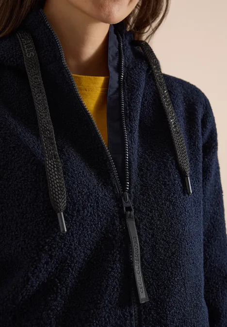 Veste polaire bleu foncé avec zip et cordon, sous lequel apparaît un t-shirt jaune.