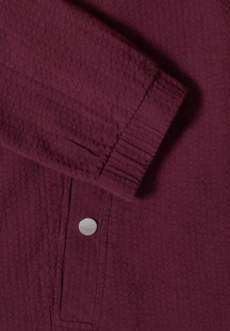 Blouson in Seersuckerqualität mit Zipper sweet grape red Nahaufnahme einer dunkelroten Jacke mit strukturiertem Stoff, elastischem Ärmelbündchen und Druckknopf-Tasche.