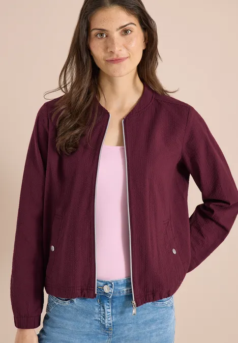 Blouson in Seersuckerqualität mit Zipper sweet grape red Frau trägt weinrote Jacke über rosa Top und Jeans