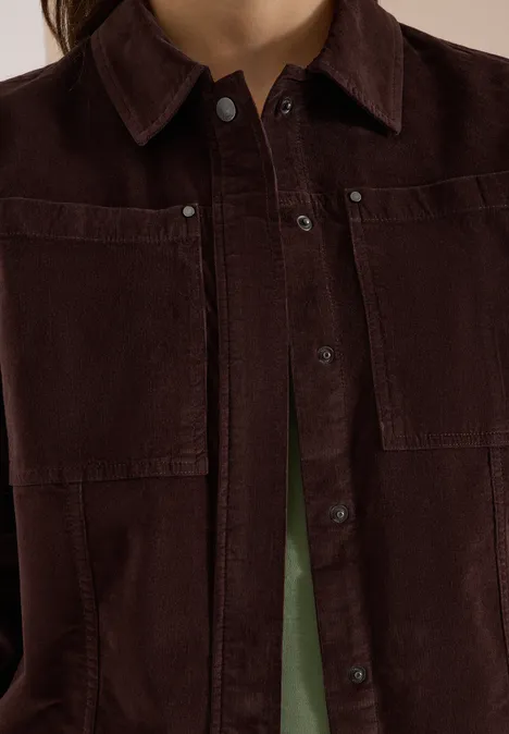 Dunkelbraune Cordjacke mit Taschen und Knopfleiste, grünes Shirt schimmert darunter.