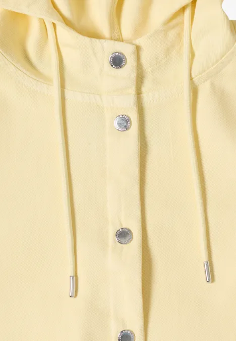 Close-up van een lichtgele hoodie met drukknopen en koord