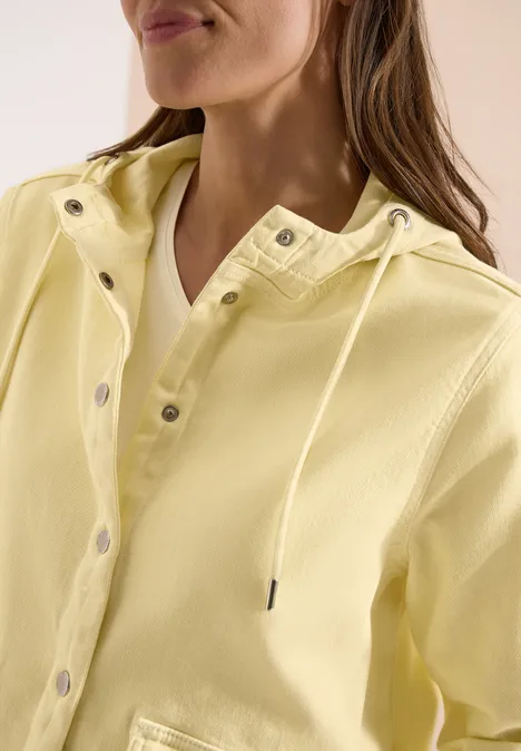 Gedeeltelijke weergave van een vrouw in een lichtgele capuchonjas met drukknopen.