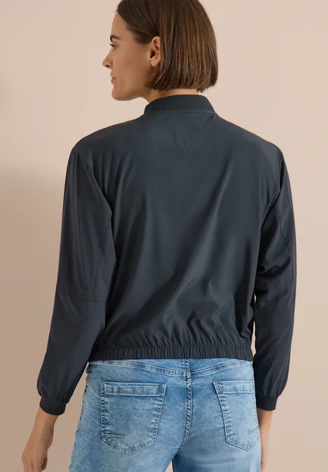 Blouson in Unifarbe mit Zipper palm breeze green Person mit dem Rücken zur Kamera, dunkle Jacke und blaue Jeans.