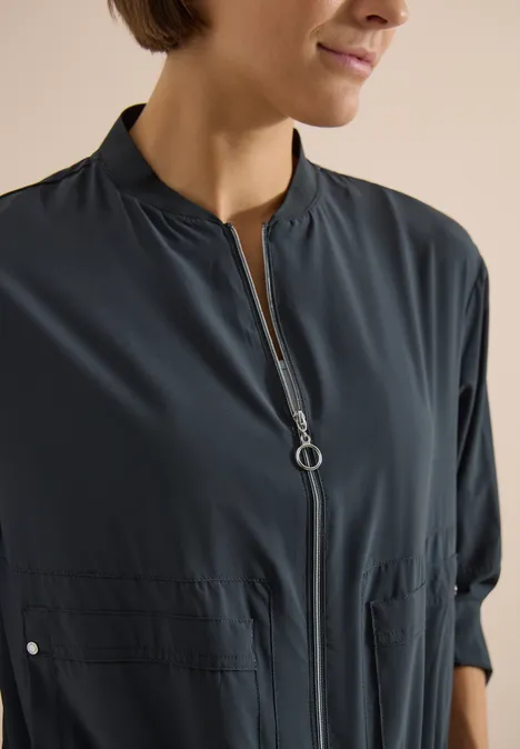 Blouson in Unifarbe mit Zipper palm breeze green Nahe Aufnahme einer Frau mit kurzem Haar in dunkler Bluse mit Reißverschluss und Stehkragen.