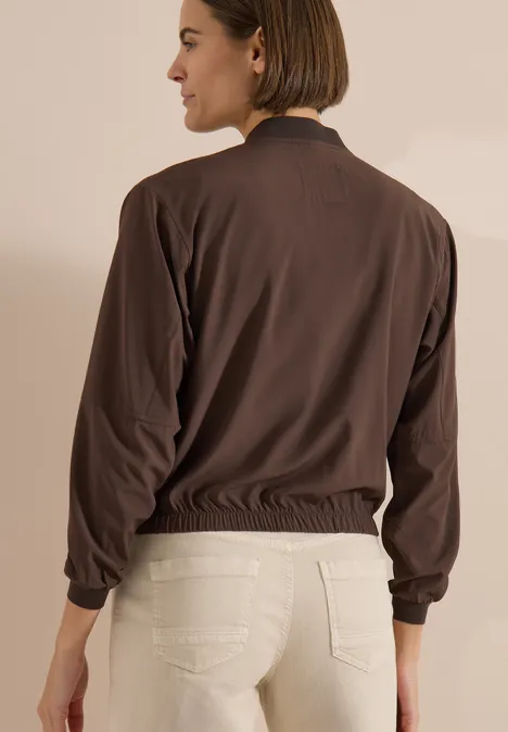 Blouson in Unifarbe mit Zipper brown cacao Rückansicht einer Frau in brauner Bomberjacke und heller Jeans vor neutralem Hintergrund.