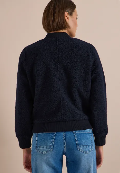 Person von hinten in navyblauer Fleecejacke und Jeans
