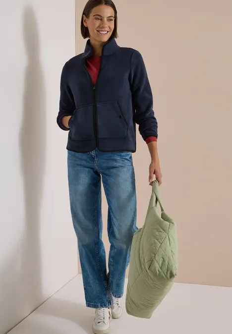 Fleecejacke mit Zipper und Stehkragen dark navy blue Frau in Jeans, marineblauer Jacke und rotem Shirt trägt eine grüne Stepp-Tasche.