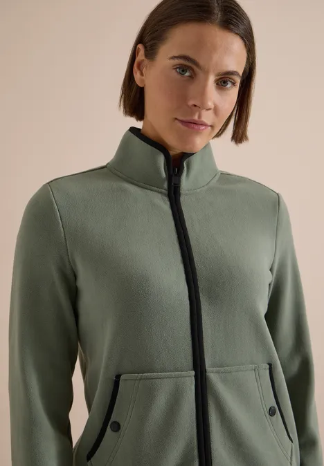 Fleecejacke mit Zipper und Stehkragen shadow khaki Frau trägt olivegrüne Fleecejacke mit Stehkragen und Reißverschluss, Kängurutaschen, schwarze Details