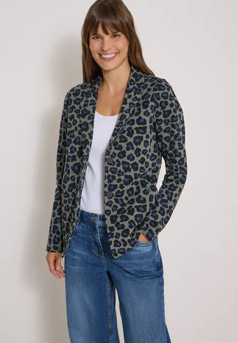 Vrouw lacht in een casual luipaardblazer met wit shirt en jeans.