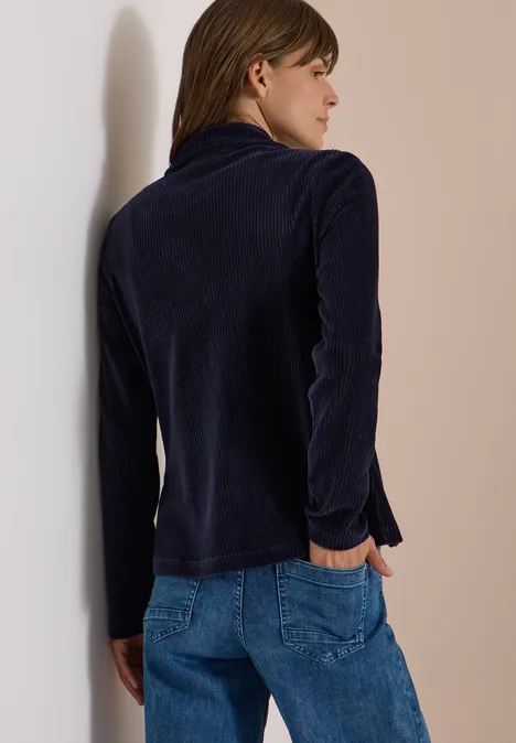 Jerseycord Blazer in Unifarbe urban dark blue Frau im Profil, trägt dunkelblauen Samtblazer und Jeans, lehnt lässig an einer Wand.
