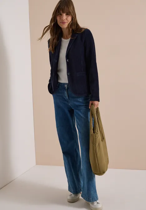 Jerseycord Blazer in Unifarbe urban dark blue Frau in weiter Jeans, weißem T-Shirt und dunkelblauem Blazer mit olivgrüner Tasche.
