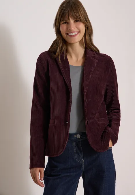 Jerseycord Blazer in Unifarbe berry red Eine lächelnde Frau trägt dunkelroten Cordblazer, graues Shirt und blaue Jeans.