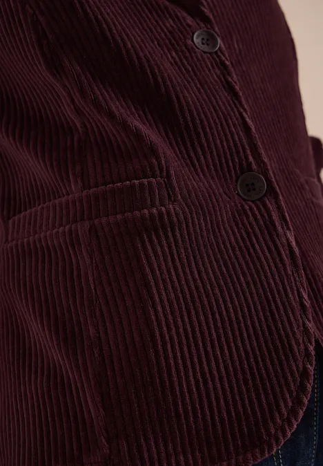 Jerseycord Blazer in Unifarbe berry red Nahaufnahme einer Person in einer burgunderroten Cord-Feinrippjacke mit Knöpfen und Tasche.
