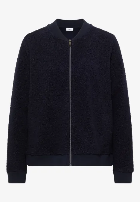 Blouson bomber en teddy bleu marine, court, zippé, avec poches latérales et bord-côtes à l'encolure et aux poignets.