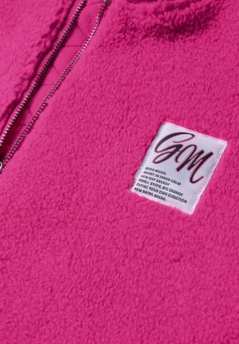 Nahaufnahme eines pinkfarbenen Fleece-Pullovers mit Reißverschluss und weißem Namensschild.