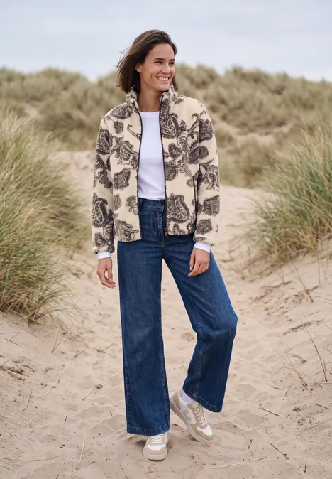 Teddyjasje met opstaande kraag en patroon teddy vanilla white Vrouw in een patroonvest, wijde jeans en sneakers op het strand