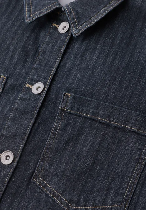 Gros plan d'une chemise en jean bleu foncé à fines rayures, boutons argentés et poche poitrine plaquée.