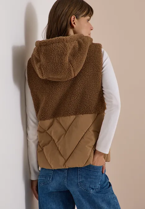 Teddy-Weste mit Steppteil und Zipper dark toffee brown Frau von hinten in brauner Fleece-Weste mit Kapuze, weißem Shirt und blauen Jeans.