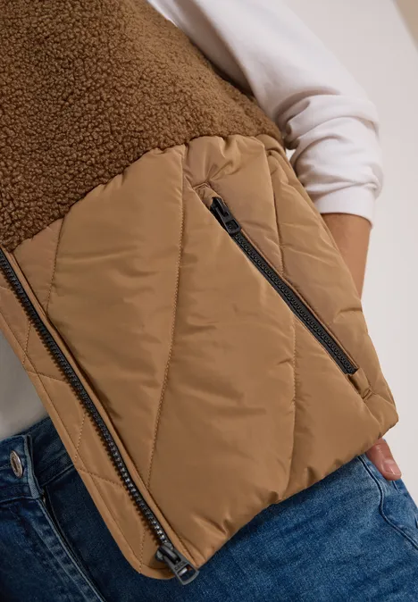 Teddy-Weste mit Steppteil und Zipper dark toffee brown Nahaufnahme: Person trägt braune gesteppte Weste mit Fleece-Einsatz und Jeans, nur Oberkörper sichtbar.