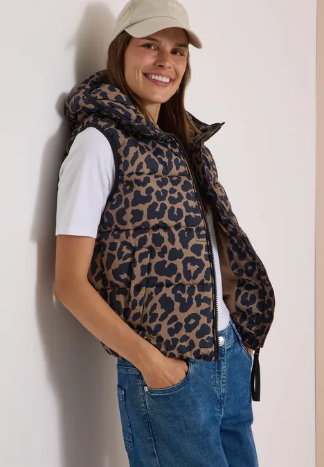 Steppweste mit Kapuze und Taschen creamy mocha Eine lächelnde Frau trägt eine gesteppte Weste mit Leopardenmuster zu weißem T-Shirt und Jeans.