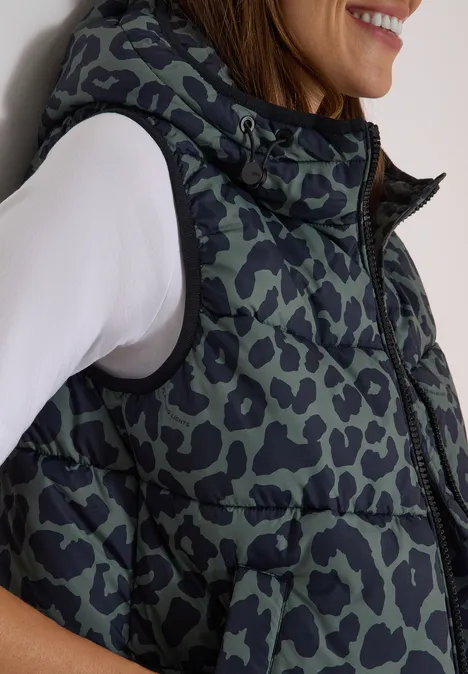 Steppweste mit Kapuze und Taschen dried olive green Seitliche Ansicht einer Frau in weißem Langarmshirt mit gesteppter, leoähnlich gemusterter Daunenweste.