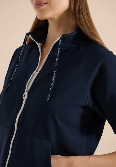 Femme portant un sweat à capuche bleu marine zippé avec poche kangourou et cordons.