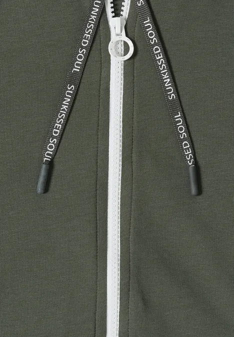 Grünes Kleidungsstück mit weißem Reißverschluss und schwarzen Kordeln mit weißem Aufdruck.