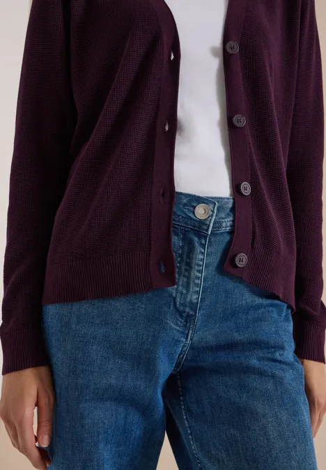 Gilet violet porté sur un t-shirt blanc et jeans bleu.