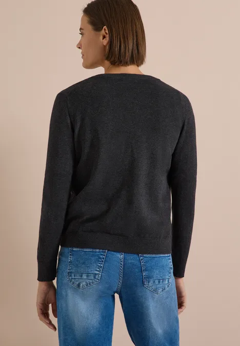 Cardigan boutonné à col rond charcoal grey melange Vue de dos d’une femme portant un pull noir et un jean bleu sur fond clair.