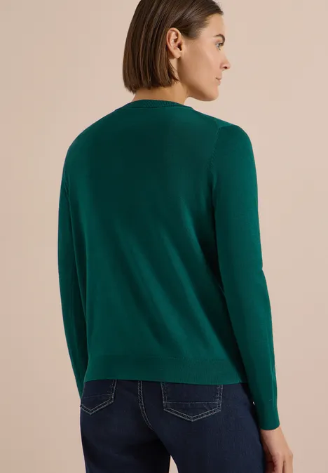 Cardigan boutonné à col rond dark fir green Femme de dos en pull vert, cheveux courts, profil latéral visible