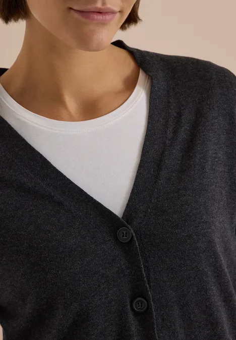 Cardigan boutonné à col V charcoal grey melange Gros plan sur un t-shirt blanc sous un cardigan gris foncé à col en V boutonné.