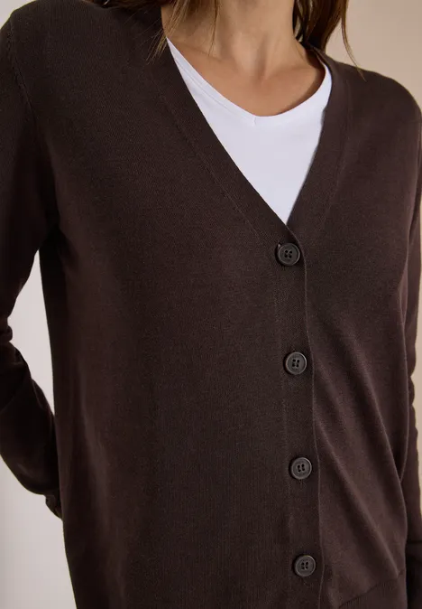 Bruine cardigan met V-hals en vijf knopen gedragen over een wit T-shirt.