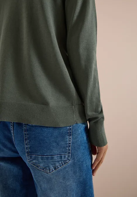 Cardigan mit V-Neck und Knopfleiste dried olive green Rückansicht einer Person in grüner Langarmbluse und blauen Jeans vor neutralem Hintergrund.