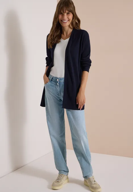 Open vest met lange mouwen urban dark blue Junge Frau in weißem T-Shirt, dunkelblauem Cardigan, weiten Jeans und Sneakern lehnt lächelnd an der Wand.